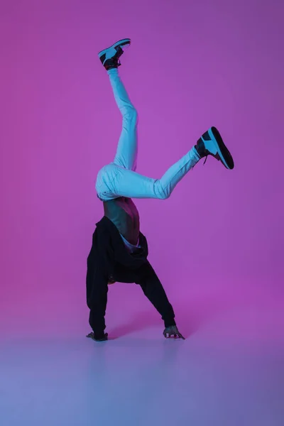 Jonge stijlvolle man in moderne straat stijl outfit geïsoleerd op gradiënt achtergrond in neon licht. Afro-Amerikaanse modieuze model in look boek, muzikant uitvoeren. — Stockfoto