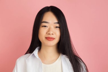 Pembe stüdyo arka planında Asyalı genç kadın portresi. İnsan duyguları kavramı, yüz ifadesi, gençlik, satış, reklam.