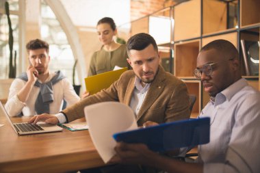 Modern ofiste birlikte çalışan meslektaşlar yaratıcı toplantı sırasında cihazlar ve aletler kullanıyorlar.
