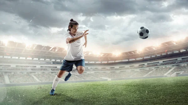 Fútbol masculino, jugador de fútbol que captura la pelota en salto en el estadio durante el partido deportivo en el fondo del cielo oscuro — Foto de Stock