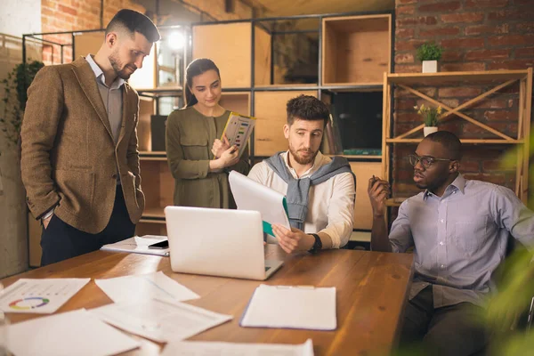 Modern ofiste birlikte çalışan meslektaşlar yaratıcı toplantı sırasında cihazlar ve aletler kullanıyorlar.