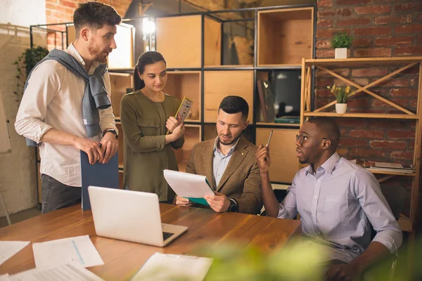 Modern ofiste birlikte çalışan meslektaşlar yaratıcı toplantı sırasında cihazlar ve aletler kullanıyorlar.
