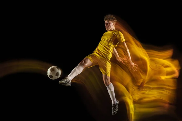 年轻的高加索男子足球或足球运动员在昏暗的背景下，为进球而踢球。健康生活方式、职业运动、业余爱好的概念. — 图库照片