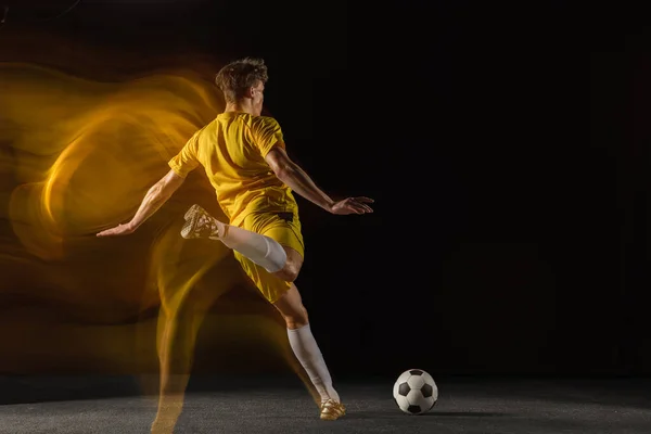 年轻的高加索男子足球或足球运动员在昏暗的背景下，为进球而踢球。健康生活方式、职业运动、业余爱好的概念. — 图库照片