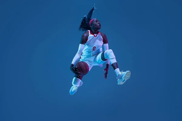 아름다운 아프리카 계 미국인 농구 선수가 푸른 배경에 네온 라이트에서 움직임 과 액션을 보여 줍니다. 건강 한 생활 방식, 직업적 인 스포츠, 취미의 개념. — 스톡 사진