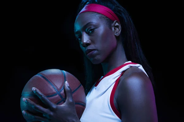 Hermosa jugadora de baloncesto afroamericana en movimiento y acción en luz de neón sobre fondo negro. Concepto de estilo de vida saludable, deporte profesional, hobby. —  Fotos de Stock