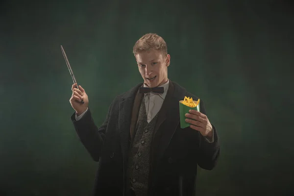 Hombre joven en acción artística aislado sobre fondo verde oscuro. Estilo retro, comparación de conceptos de eras. — Foto de Stock