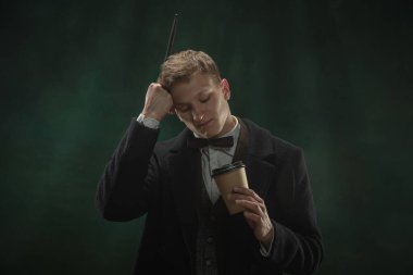 Sanattaki genç adam koyu yeşil arka planda izole edilmiş. Retro biçimi, dönemin karşılaştırması.