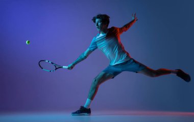 Tenis oynayan beyaz bir adam mor-mavi stüdyo arka planında, neon, aksiyon ve hareket konseptiyle izole edilmiş.