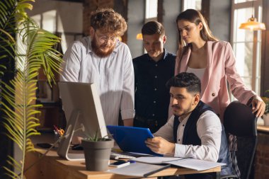 Modern ofiste birlikte çalışan meslektaşlar yaratıcı toplantı sırasında cihazlar ve aletler kullanıyorlar.