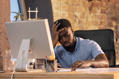 Afrikalı işadamı, modern ofiste cihaz ve aletler kullanarak çalışan bir yönetici.