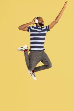 Bir Afrikalı genç, sarı stüdyo arkaplanının üzerinden atlıyor. Reklam için kopyalama alanı var.