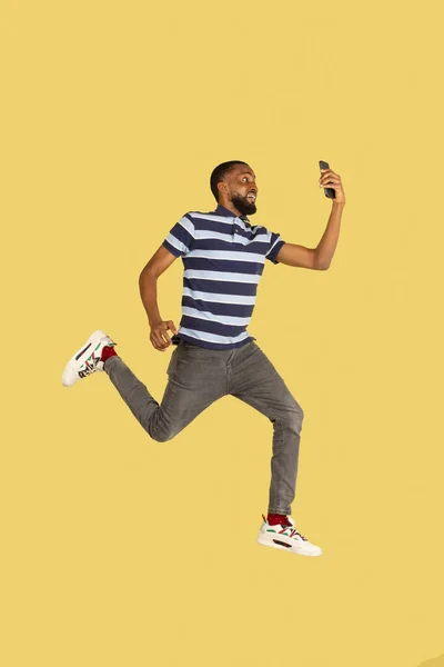 Один африканський юнак стрибає в ізоляції через жовте тло студії з авторським простором для реклами — стокове фото