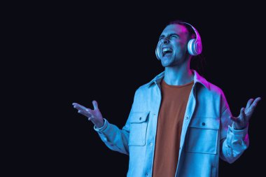 Kafkasyalı genç adam, Neon 'daki karanlık stüdyo arka planında portre çiziyor. İnsan duyguları kavramı, yüz ifadesi.