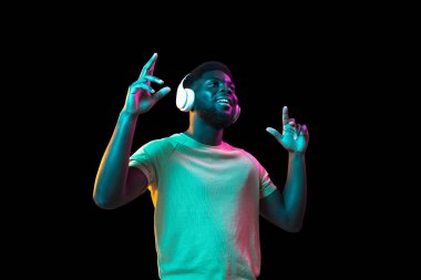 Afrikalı genç adamlar Neon 'daki karanlık stüdyo arka planında portre çiziyorlar. İnsan duyguları kavramı, yüz ifadesi, gençlik, satış, reklam.