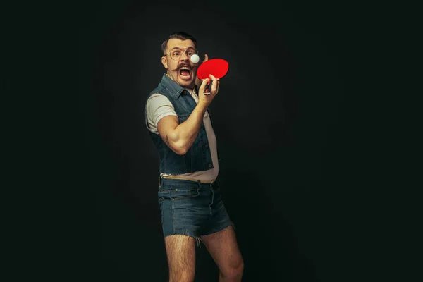 Jovem caucasiano jogando tênis isolado no fundo do estúdio preto em estilo retro, ação e conceito de movimento — Fotografia de Stock