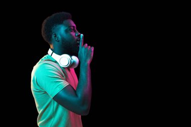 Afrikalı genç adamlar Neon 'daki karanlık stüdyo arka planında portre çiziyorlar. İnsan duyguları kavramı, yüz ifadesi, gençlik, satış, reklam.