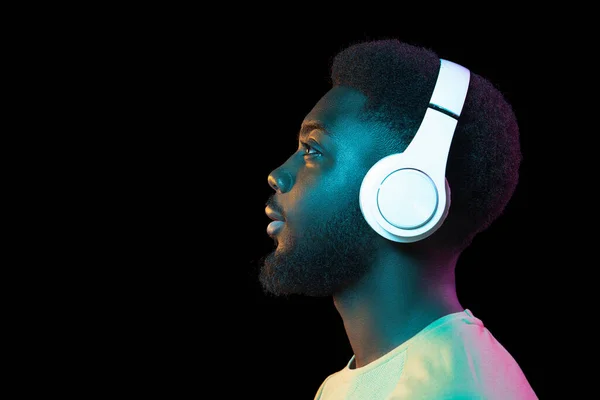 Afrikanisches Porträt junger Männer auf dunklem Studiohintergrund in Neon. Konzept menschlicher Emotionen, Mimik, Jugend, Verkauf, Werbung. — Stockfoto