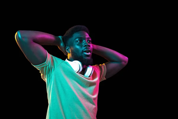 在霓虹灯的黑暗工作室背景上的非洲年轻人肖像。人类情感、面部表情、青春、销售、广告的概念. — 图库照片