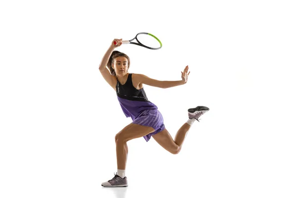 Jeune femme caucasienne jouant au tennis isolé sur fond de studio blanc en action et mouvement, concept sportif — Photo