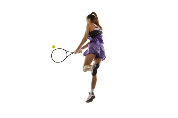 Jeune femme caucasienne jouant au tennis isolé sur fond de studio blanc en action et mouvement, concept sportif — Photo