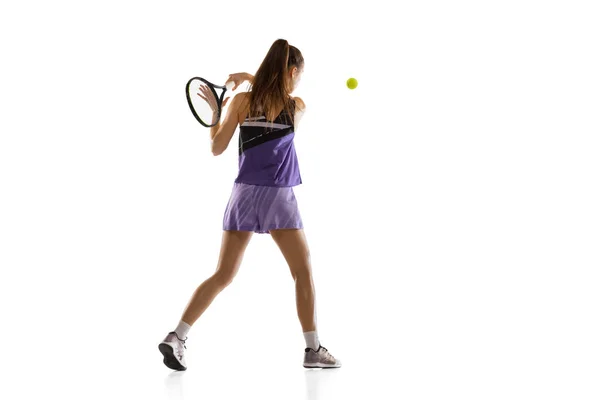 Jeune femme caucasienne jouant au tennis isolé sur fond de studio blanc en action et mouvement, concept sportif — Photo