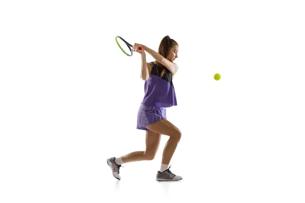 Молодая кавказская женщина, играющая в теннис на белом фоне студии в действии и движении, спортивная концепция — стоковое фото