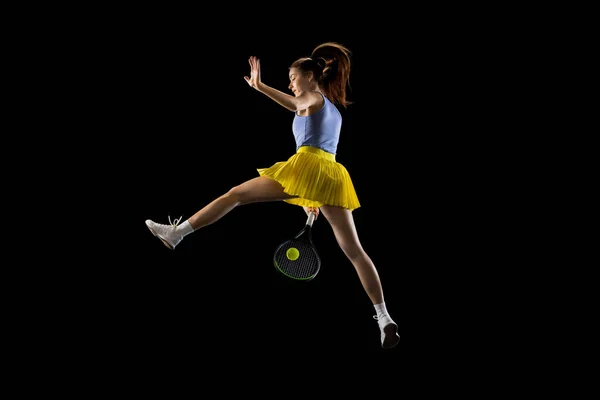 Junge kaukasische Frau spielt Tennis isoliert auf schwarzem Studiohintergrund in Aktion und Bewegung, Sportkonzept — Stockfoto