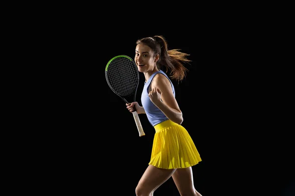 若い白人女性は、アクションと動きで黒のスタジオの背景に隔離されたテニスをプレイ,スポーツの概念 — ストック写真