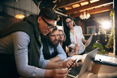 Modern ofiste birlikte çalışan meslektaşlar yaratıcı toplantı sırasında cihazlar ve aletler kullanıyorlar.