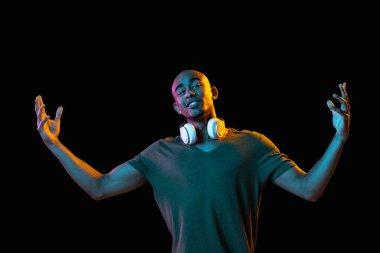 Siyah stüdyo arka planında Neon 'lu Afro-Amerikalı genç adam portresi. İnsan duyguları kavramı, yüz ifadesi, gençlik, satış, reklam.