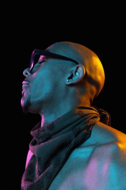 Siyah stüdyo arka planında neon rengi Afro-Amerikan genç adam portresi. Moda kavramı, erkekler güzellik, gençlik kültürü, performans.