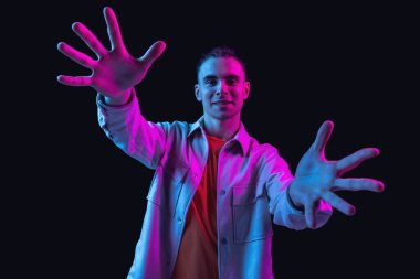 Kafkasyalı genç adam, Neon 'daki karanlık stüdyo arka planında portre çiziyor. İnsan duyguları kavramı, yüz ifadesi.