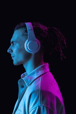 Kafkasyalı genç adam, Neon 'daki karanlık stüdyo arka planında izole edilmiş. Yan görünüm