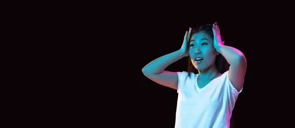 Asiatice tinere portret pe fundal studio întuneric în neon. Conceptul de emoții umane, expresie facială, tineret, vânzări, anunț . — Fotografie, imagine de stoc
