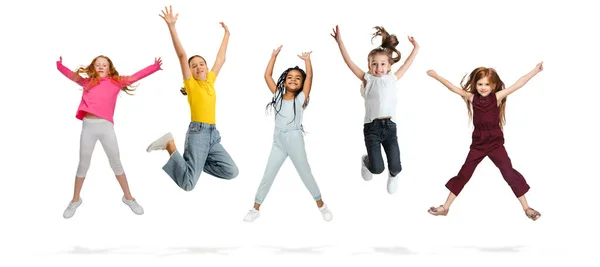 Ομάδα παιδιών του δημοτικού σχολείου ή μαθητές που πηδούν σε χρωματιστά casual ρούχα σε λευκό φόντο στούντιο. Δημιουργικό κολάζ. — Φωτογραφία Αρχείου