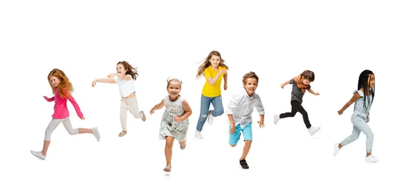 Gruppo di bambini delle scuole elementari o alunni che corrono in abiti casual colorati su sfondo bianco studio. Collage creativo. — Foto Stock