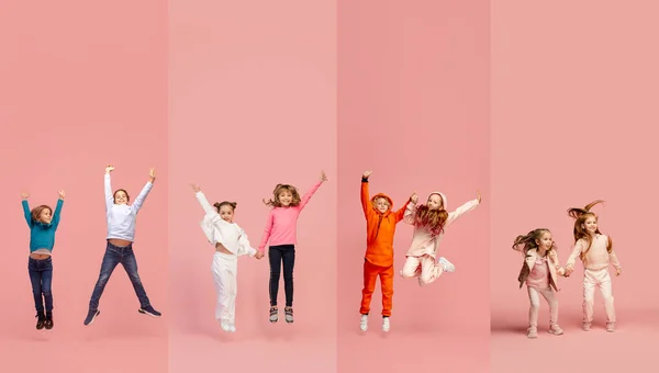 Sekelompok anak sekolah dasar atau murid melompat dalam pakaian kasual berwarna-warni di latar belakang studio merah muda. Kolase kreatif. — Stok Foto