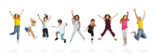 Grupa dzieci szkoły podstawowej lub uczniów skaczących w kolorowe ubrania casual na białym tle studio. Kreatywny kolaż. Zdjęcia Stockowe bez tantiem