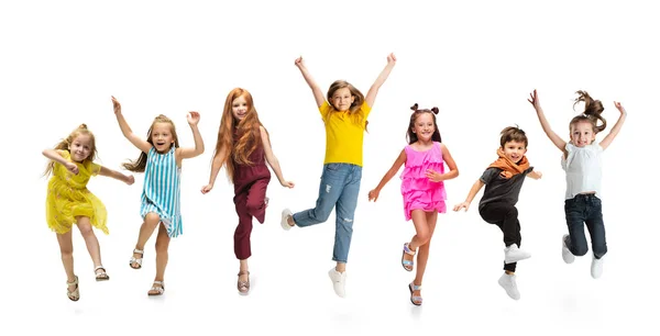 Group of elementary school kids or pupils jumping in colorful casual clothes on white studio background. Creative collage. Stock Picture