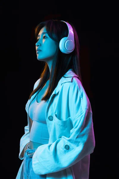 Azjatycki młody kobieta portret na ciemny studio tło w neon. Pojęcie ludzkich emocji, ekspresji twarzy, młodzieży, sprzedaży, reklamy. — Zdjęcie stockowe