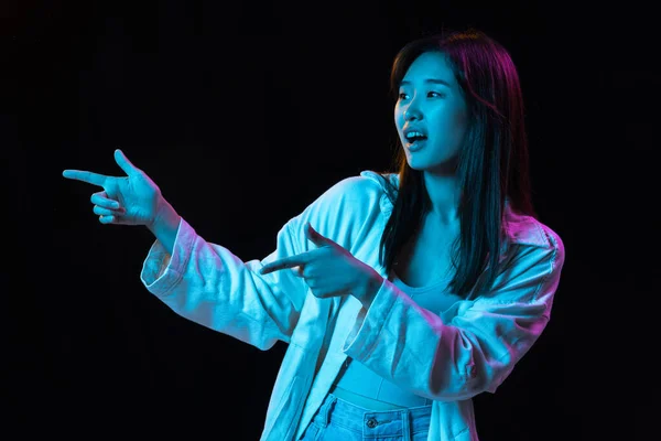 在霓虹灯的黑暗工作室背景上的亚洲年轻女性肖像。人类情感、面部表情、青春、销售、广告的概念. — 图库照片