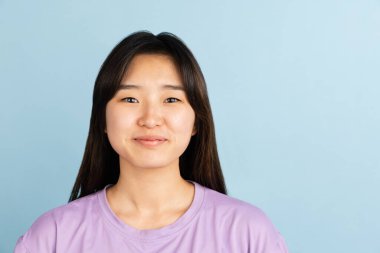 Mavi stüdyo arka planında Asyalı genç kadın portresi. İnsan duyguları kavramı, yüz ifadesi, gençlik, satış, reklam.