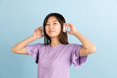 Mavi stüdyo arka planında Asyalı genç kadın portresi. İnsan duyguları kavramı, yüz ifadesi, gençlik, satış, reklam.