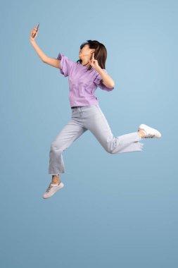 Mavi stüdyo arka planında Asyalı genç kadın portresi. İnsan duyguları kavramı, yüz ifadesi, gençlik, satış, reklam.