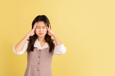 Sarı stüdyo arka planında Asyalı genç kadın portresi. İnsan duyguları kavramı, yüz ifadesi, gençlik, satış, reklam.