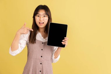 Sarı stüdyo arka planında Asyalı genç kadın portresi. İnsan duyguları kavramı, yüz ifadesi, gençlik, satış, reklam.