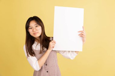 Sarı stüdyo arka planında Asyalı genç kadın portresi. İnsan duyguları kavramı, yüz ifadesi, gençlik, satış, reklam.