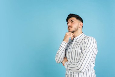 Mavi stüdyo arka planında genç adam portresi. İnsan duyguları kavramı, yüz ifadesi, gençlik, satış, reklam.