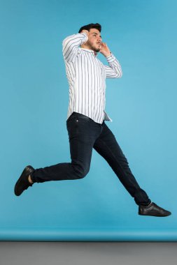 Mavi stüdyo arka planında genç adam portresi. İnsan duyguları kavramı, yüz ifadesi, gençlik, satış, reklam.